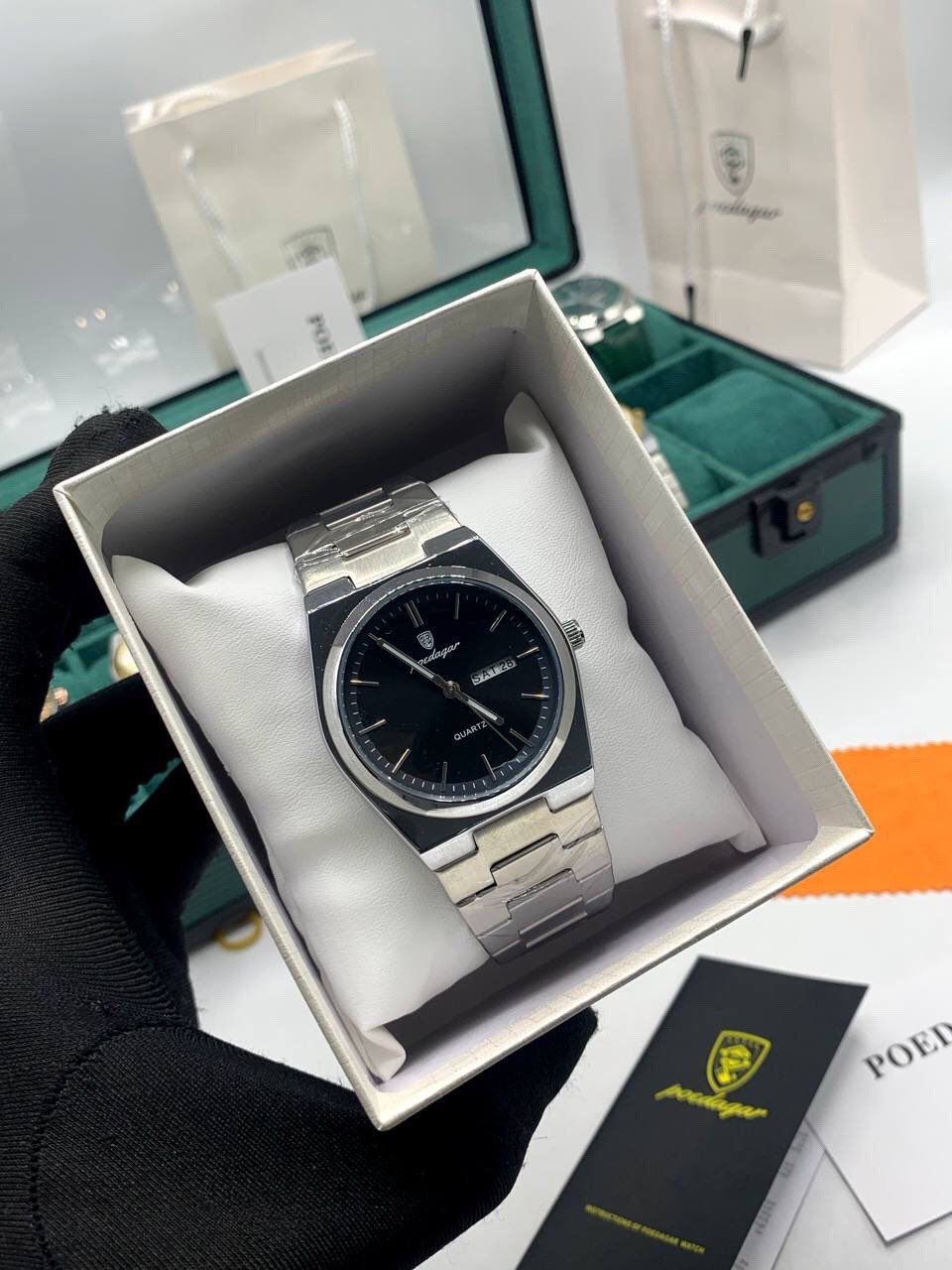 Montre de luxe Poedagar pour homme avec cadran noir soleillé, affichage de la date et du jour, et bracelet en acier inoxydable argenté.